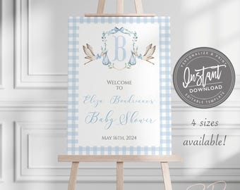 May include: A baby shower welcome sign on a wooden easel. The sign has a blue and white gingham border and features text that reads "Welcome to Eliza Boudreaux's Baby Shower, May 16th, 2024." The sign also includes a stork illustration.