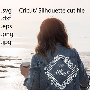 May include: A denim jacket with a white floral design and the text "mrs. Albert" in a diamond shape.