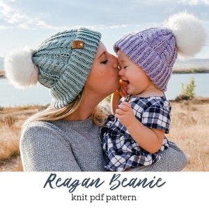 Puede incluir: Una mujer y un bebé con gorros de punto a juego con pompones de piel sintética. El gorro de la mujer es verde claro y el del bebé es morado. La imagen incluye el texto "Reagan Beanie knit pdf pattern".