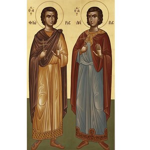 Può includere: Un'icona che raffigura due figure in abiti religiosi tradizionali. La figura a sinistra indossa una veste marrone sopra un abito dorato, mentre la figura a destra indossa una veste blu sopra un abito rosso. Entrambe le figure tengono una croce nella mano destra e hanno la mano sinistra alzata in un gesto di benedizione. L'icona è dipinta in uno stile tradizionale con colori vivaci e dettagli intricati.