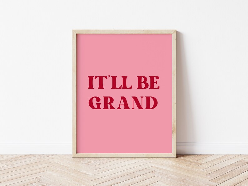 Puede incluir: Un p&oacute;ster rosa enmarcado con el texto "IT'LL BE GRAND" en rojo.