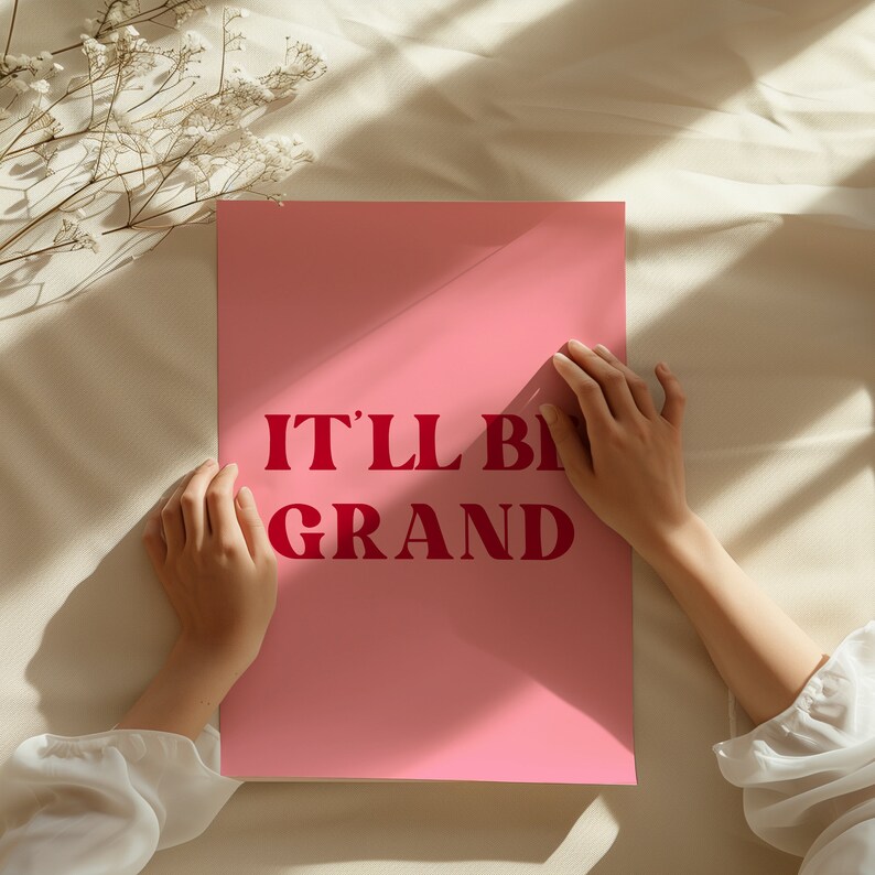 Puede incluir: P&oacute;ster rosa con el texto "IT'LL BE GRAND" en letras rojas.