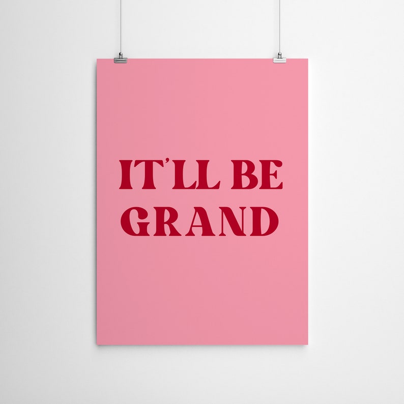 Puede incluir: P&oacute;ster rosa con el texto "IT'LL BE GRAND" en rojo.