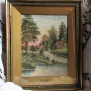 May include: A framed watercolor painting depicting a rural landscape with a winding stream, lush greenery, and a small cottage nestled among the trees. The painting is set against a backdrop of a soft pink and orange sunset.