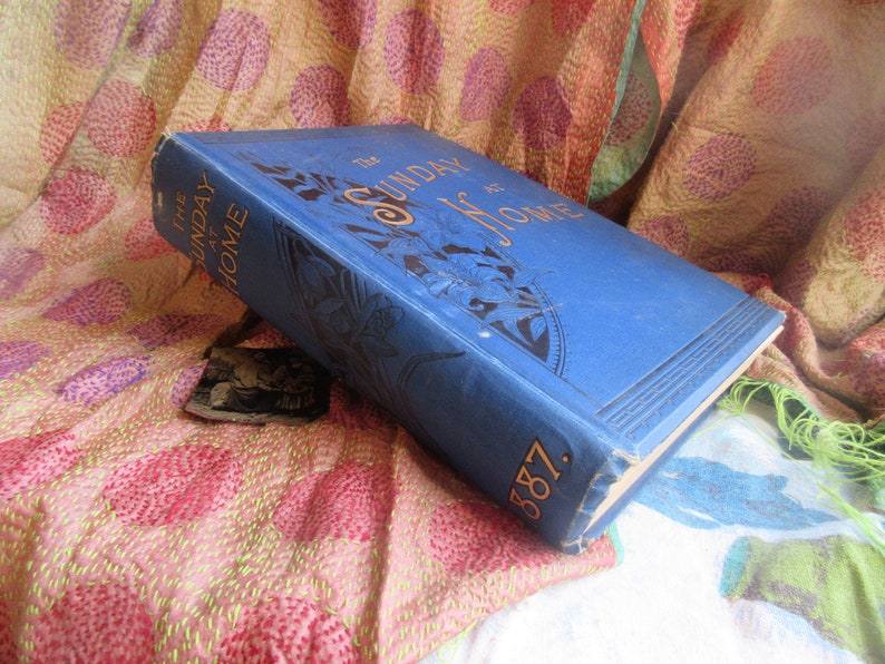 May include: A blue book with gold lettering that reads 'The Sunday at Home 1887'.
