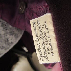 May include: A close-up of a brown leather label with white text that reads "Leather Cleaning & Service Division 835 Bergen St. Newark, N.J. 07112"