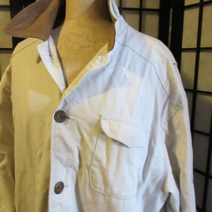 May include: A white cotton jacket with a brown corduroy collar. The jacket has a button closure and a single pocket on the left side.