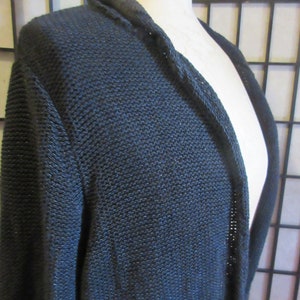 May include: A black open-front cardigan sweater with a loose fit and a knit texture.
