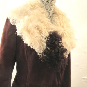 May include: A brown suede jacket with a large, fluffy white and black fur collar.