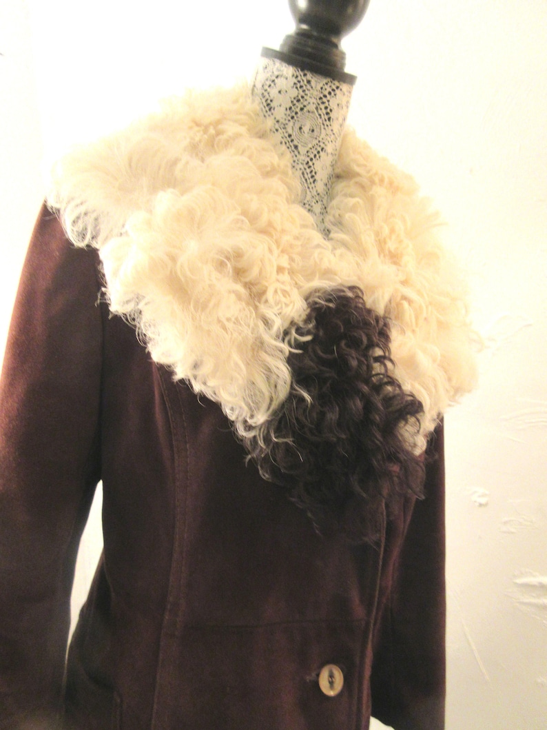 May include: A brown suede jacket with a large, fluffy white and black fur collar.