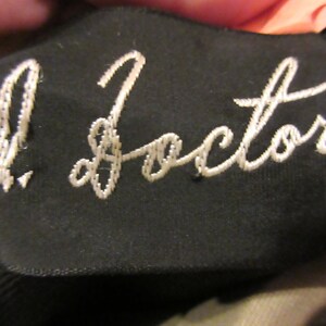 May include: A black fabric patch with white embroidery that reads "J. Factor".