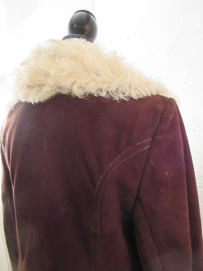 May include: A brown suede jacket with a white faux fur collar. The jacket has a seam down the back.