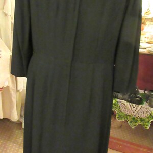 May include: A black dress with a long sleeve and a back zipper. The dress has a fitted bodice and a slightly flared skirt.