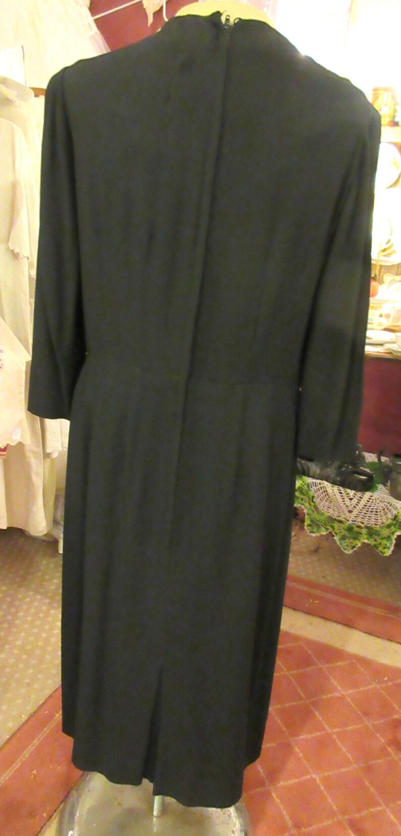 May include: A black dress with a long sleeve and a back zipper. The dress has a fitted bodice and a slightly flared skirt.