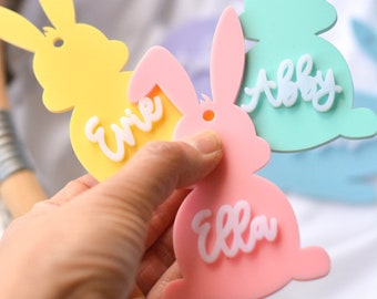 May include: Three pastel colored bunny shaped tags with the names "Ellie", "Abby", and "Ernie" written in white.