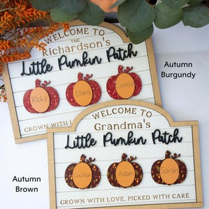 Peut inclure: Deux panneaux en bois avec un fond blanc et un cadre en bois. Les panneaux indiquent "Bienvenue au Little Pumpkin Patch" avec des découpes de citrouilles personnalisées. Un panneau est en bordeaux d'automne et l'autre en marron d'automne.