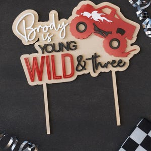 Niestandardowa akrylowa ozdoba na tort z motywem "Young Wild and Three Monster Truck" na trzecie urodziny malucha w kolorze czerwonym i czarnym