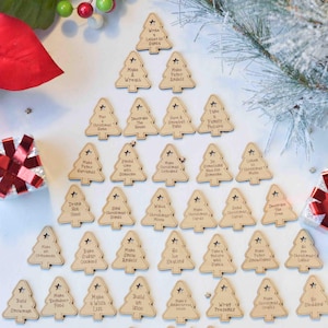 May include: A set of 25 wooden Christmas tree decorations with various festive activities written on them, such as "Write a Letter to Santa", "Make a Wreath", "Make Paper Angels", "Decorate the House", "Have a Snowball Fight", "Take a Family Picture", "Play a Christmas Game", "Make Peanut Brittle", "Spend Time with Someone", "Make Christmas Cookies", "Do Something Nice for Someone", "Listen to Christmas Music", "Drink Hot Chocolate", "Sing Christmas Carols", "Watch a Christmas Movie", "Make Christmas Cards", "Give Christmas Presents", "Decorate the Tree", "Make Ornaments", "Bake Sugar Cookies", "Make Snow Angels", "Go Ice Skating", "Take a Nature Walk with a Friend", "Make Gingerbread Cookies", "Go Christmas Caroling", "Build a Snowman", "Make Reindeer Food", "Make a Wish List", "Build an Igloo", "Make a Christmas House", "Wrap Presents", "Make Christmas Crafts", "Go Sledding", "Drink Eggnog", "Donate a Present", "Go Ice Skating".