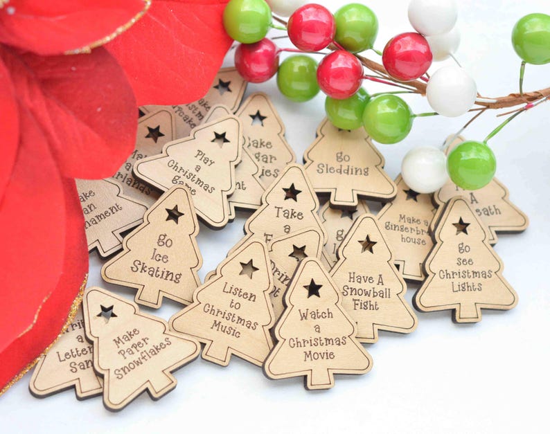 K&ouml;nnte beinhalten: Weihnachtsbaum-Ornamente aus Holz mit verschiedenen festlichen Aktivit&auml;ten, die darauf geschrieben sind, wie "Spiele ein Weihnachts-Spiel", "Gehe Schlittschuhlaufen", "Bastel Papier-Schneeflocken", "Schau dir einen Weihnachtsfilm an" und "Hab eine Schneeballschlacht".