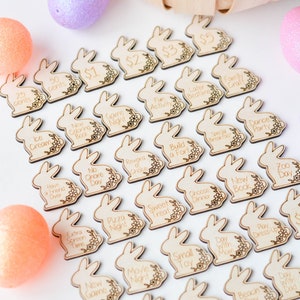 May include: Wooden bunny-shaped tokens with various activities and monetary values engraved on them. The tokens are surrounded by decorative Easter eggs and a basket. Activities include "Ice Cream," "Game Night," and "Build a Fort."