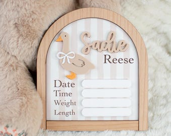 May include: Wooden nursery sign with a duck illustration and the name "Sadie Reese". The sign has space to record date, time, weight, and length. The background features vertical stripes in beige and white.