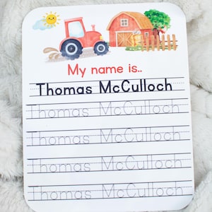 May include: A rectangular white practice writing board featuring a colorful farm scene with a red tractor, a barn, and a sun. The text reads My name is.. followed by the name Thomas McCulloch in solid and dotted lines for tracing practice.