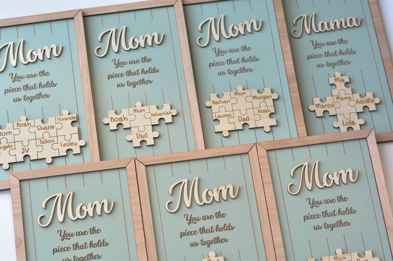 Puede incluir: Arte de pared enmarcado en madera con la palabra "Mom" en fuente cursiva y la frase "You are the piece that holds us together." Cada pieza tiene un dise&ntilde;o de rompecabezas con nombres. El fondo es azul claro.