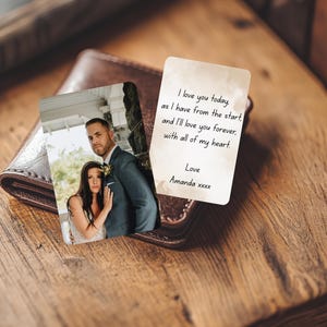 May include: A brown leather wallet with two cards. One card features a photo of a couple, and the other card has handwritten text that reads "I love you today...with all of my heart." The cards are on a wooden surface.