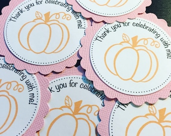May include: Pink and white round favor tags with a scalloped edge. Each tag features a pumpkin outline in orange and the text "Thank you for celebrating with me!"