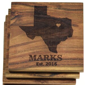 May include: Set of four wooden coasters featuring a laser-engraved outline of the state of Texas with a heart in the center. The coasters are personalized with the text "MARKS Est. 2016".