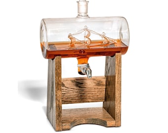 May include: A clear glass decanter with a ship inside, filled with amber liquid, on a wooden stand with a spigot.