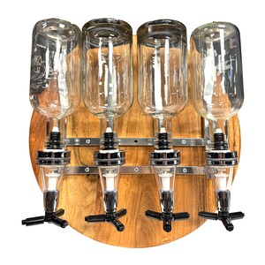 May include: A wooden wall-mounted liquor dispenser with four clear glass bottles and chrome spouts. The dispenser has a round wooden base and metal brackets.