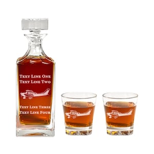 May include: A crystal decanter and two matching glasses with a small airplane design etched on them. The decanter has the text "TEXT LINE ONE TEXT LINE TWO TEXT LINE THREE TEXT LINE FOUR" etched on it.