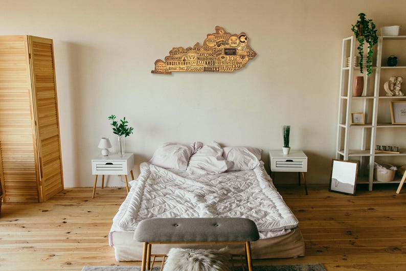 Pu&ograve; includere: Un'opera d'arte murale in legno a forma dello stato del Kentucky con i nomi delle citt&agrave; e dei paesi di tutto lo stato. L'opera d'arte &egrave; appesa a una parete di una camera da letto con un letto, comodini e una libreria.