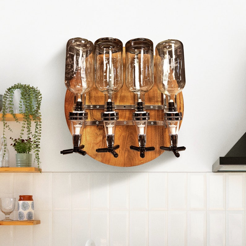 May include: A wooden wall-mounted liquor dispenser with four clear glass bottles and metal spouts. The dispenser has a circular shape and is made of light brown wood.