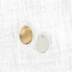 May include: Two round metal charms, one gold and one silver, with a hole at the top for attaching to a necklace or bracelet.