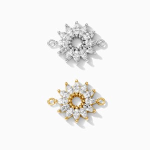 May include: Two silver and gold tone connector charms with a circle of marquise shaped clear stones. The charms have a loop on each side for attaching to a necklace or bracelet.