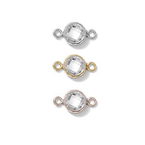 May include: Three round, faceted crystal connectors in silver, gold, and rose gold. Each connector has a clear, sparkling crystal center and small loops on either side for attaching to other jewelry components. The connectors are displayed against a white background.