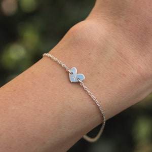 May include: A silver chain bracelet with a heart-shaped charm engraved with the letter "A".