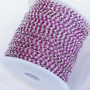 May include: A spool of silver chain with a purple enamel coating. The chain is wound around a white plastic spool.