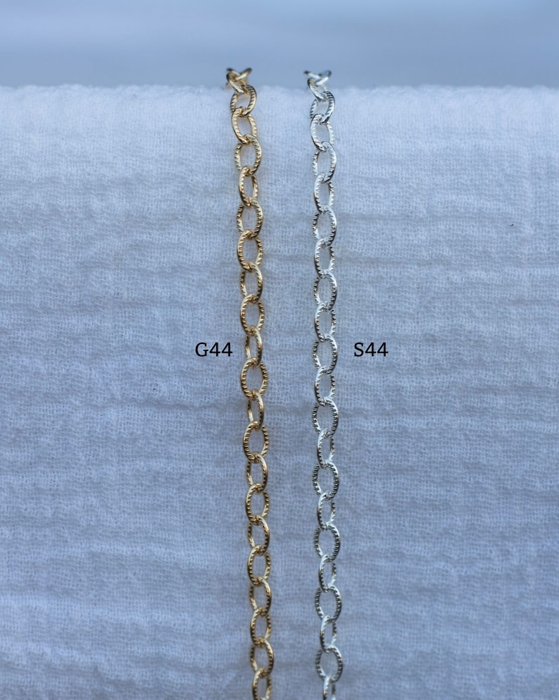 Op de afbeelding: Twee kettingen, een gouden en een zilveren, worden getoond tegen een witte achtergrond. De gouden ketting is gemarkeerd met "G44" en de zilveren ketting met "S44".