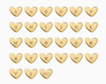 May include: A collection of gold-colored heart-shaped charms, each engraved with a letter of the alphabet or the infinity symbol. The charms are arranged in rows and columns against a white background. Each charm has a small hole at the top.
