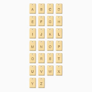 May include: A collection of gold-colored rectangular charms, each engraved with a letter of the alphabet from A to Z. Each charm has a small hole at the top. The charms are arranged in rows and columns against a white background.