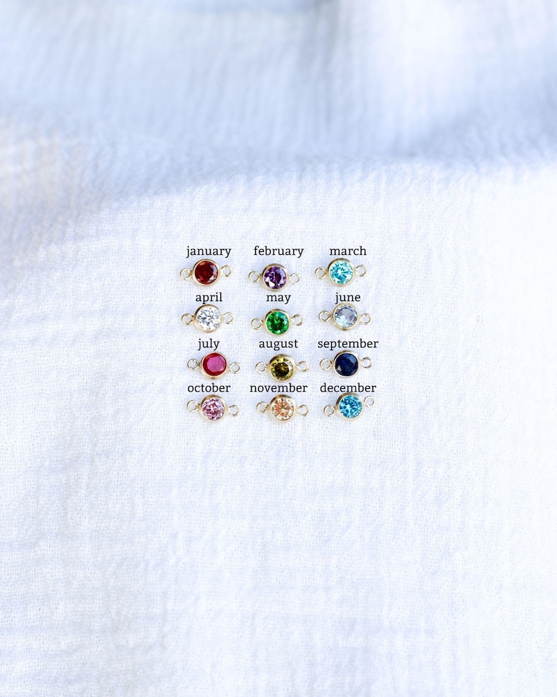 May include: Twelve gold charms with colored gemstones, each representing a different month of the year. January is red, February is purple, March is blue, April is white, May is green, June is light blue, July is red, August is green, September is blue, October is pink, November is yellow, and December is blue.
