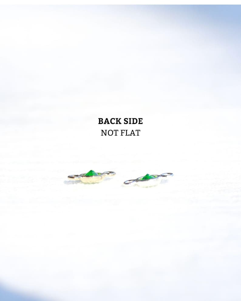 May include: Two close-up images of a green gemstone charm with a gold and silver setting. The text "BACK SIDE NOT FLAT" is visible in the image.