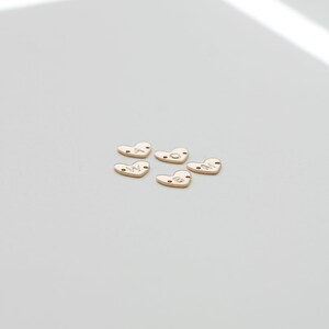 May include: Five gold heart-shaped charms with the letters W, O, M, A, and N engraved on them.