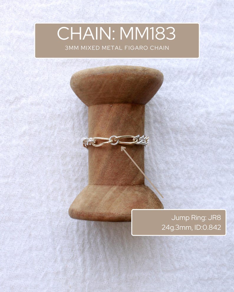 May include: A silver and gold mixed metal Figaro chain, 3mm wide, is shown on a wooden spool. The image also shows a jump ring with the text "Jump Ring: JR8 24g.3mm, ID:0.842" and the text "CHAIN: MM183 3MM MIXED METAL FIGARO CHAIN". The chain is a jewellery item.