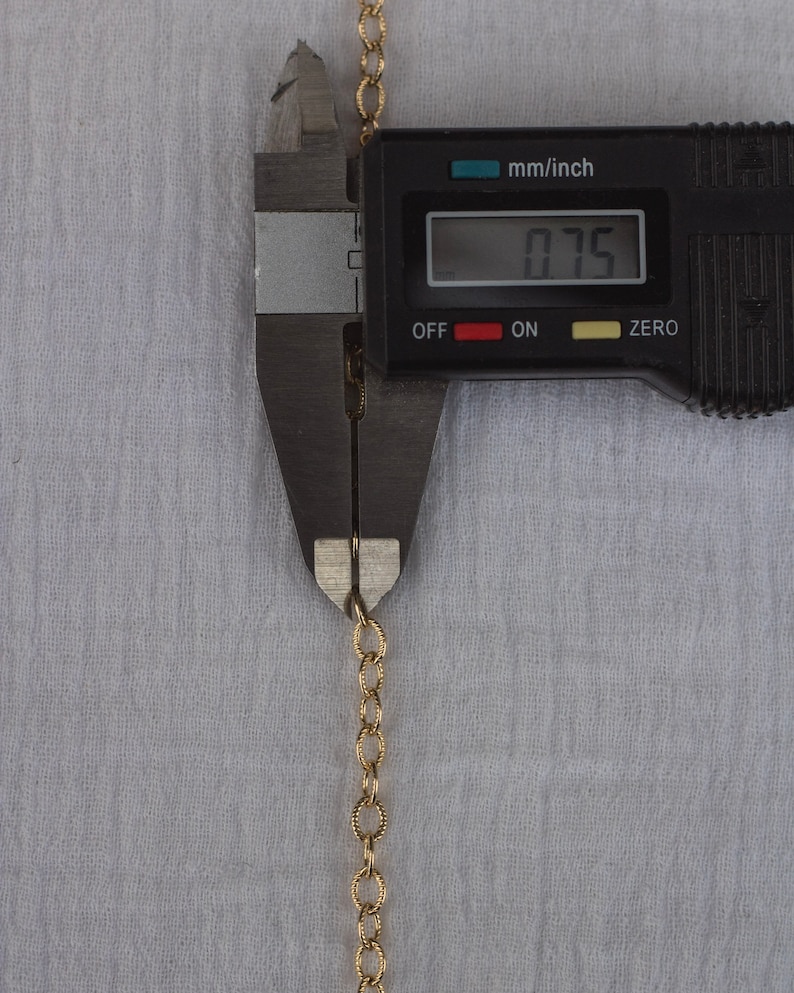 Op de afbeelding: Een gouden ketting wordt gemeten met een digitale schuifmaat. De schuifmaat geeft 0,75 mm/inch aan.