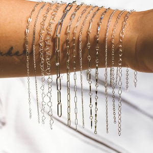 May include: A collection of silver chain bracelets with different link styles, including heart, oval, and square links.