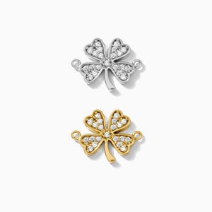 May include: Two four-leaf clover charms, one silver and one gold, each with clear sparkling stones.